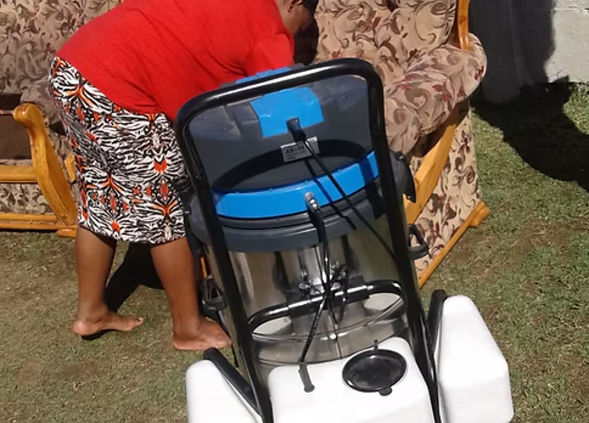 A Mizo Hygiene Services cleaner deep cleaning a couch with a professional carpet and upholstery extractor